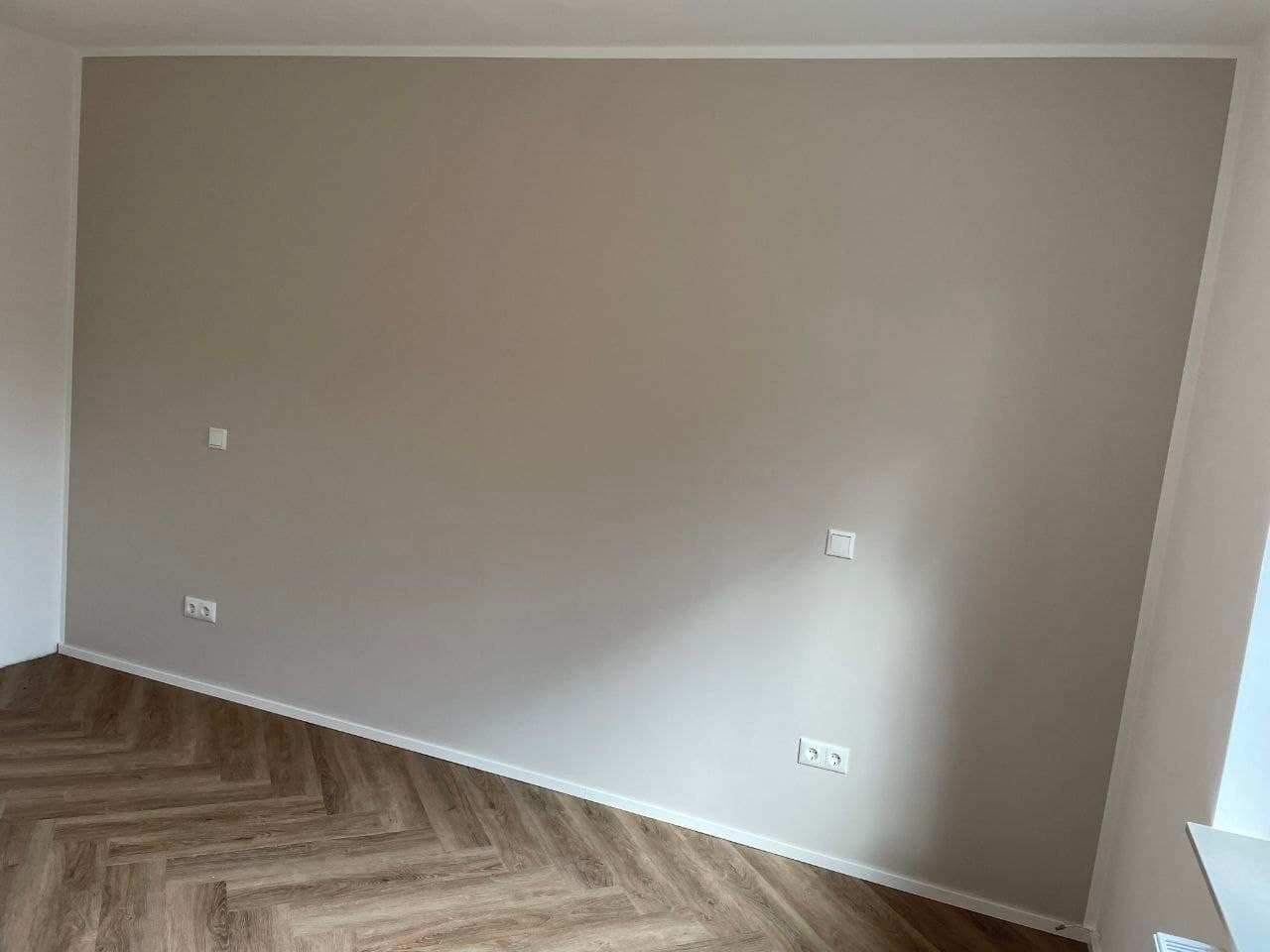 Wohnraum mit einer greige gestrichenen Wandfläche, die an der Kante randscharf zur weißen Nachbarwand abschließt